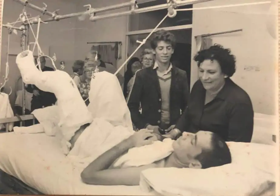 מרים זנזורי ליד מיטתו של בנה יהודה זנזורי לאחר שנפצע ביום כיפור ולידה קובי זנזורי. צילום: באדיבות המשפחה