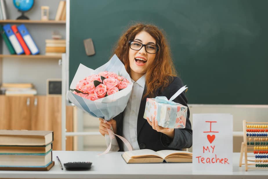ביי פוסט קרדיט תמונה FREEPIKexcited-young-female-teacher-holding-bouquet-with-gift-sitting-desk-with-school-tools-classroom