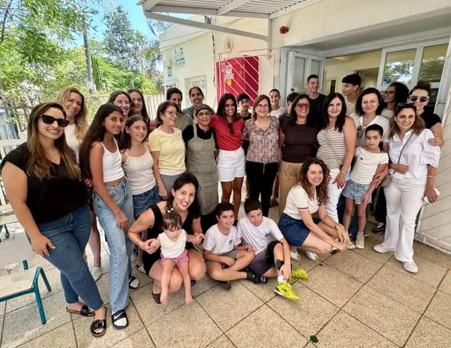 הגננת רונית מאסטי עם רה״ע ליזי דלריצ׳ה ובוגרות ובוגרי גן מרגנית מכל המחזורים שבאו ללוות אותה ביום האחרון שלה בגן. צילום: דוברות עיריית גני תקווה