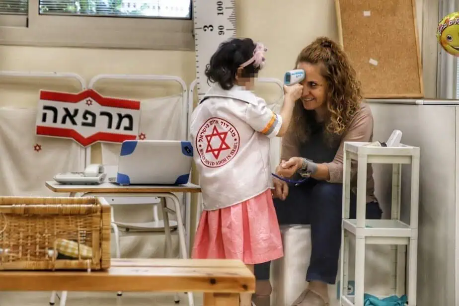 ילדה מודדת חום למנהלת גן החלומות. צילום: איתן אלחדז ברק